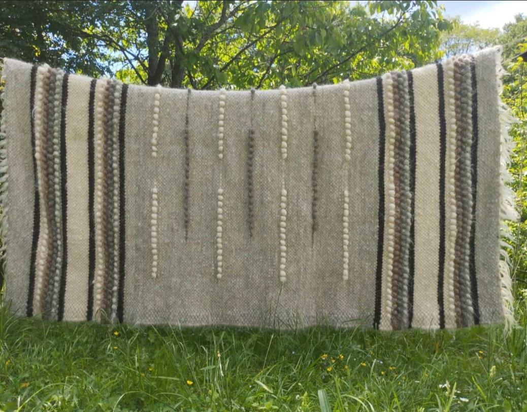 Large handmade wool blanket elegantly displayed on a rustic wooden fence, highlighting its premium quality and intricate detailing